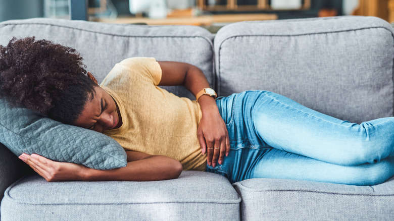 Woman on couch holding stomach