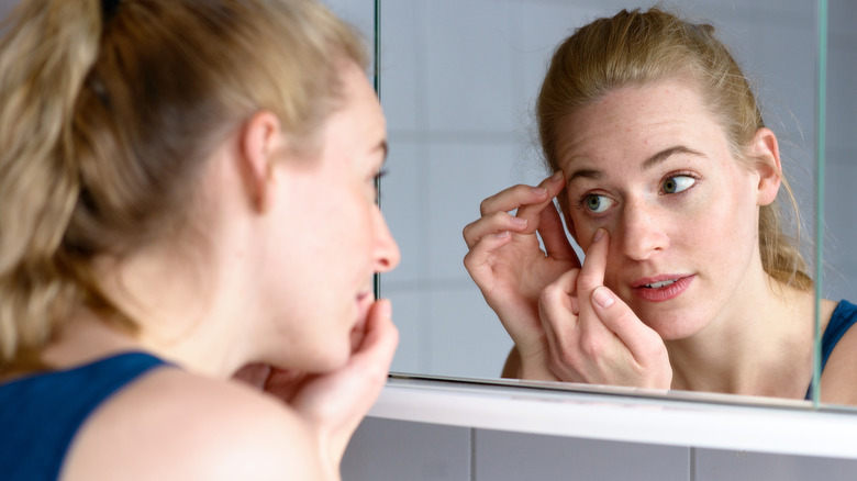 Woman looking at her eye in the mirror