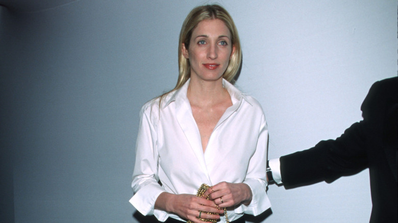 Carolyn Bessette-Kennedy at an event wearing a white shirt and black trousers