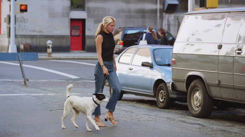 Carolyn Bessette Kennedy walking her dog in New York in jeans and a black tank top