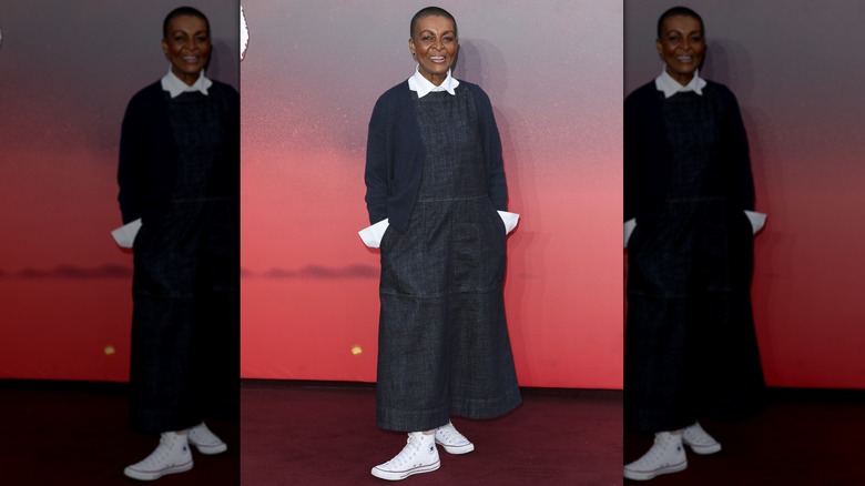 Adjoa Andoh posing on the red carpet in a denim dress and white Chuck Taylors