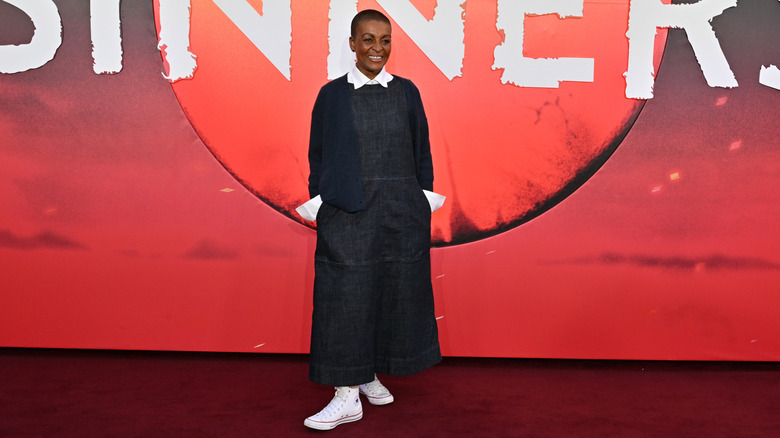 A woman sitting cross-legged wearing red sneakers and jeans