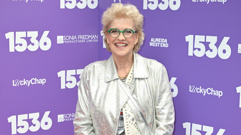 Hilary Gish Whitehall smiling while wearing a silver jacket and green eyeglasses at a West End opening night event in 2026