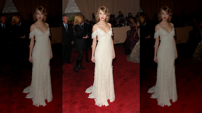 Taylor Swift on the red carpet in a white gown with exposed shoulders