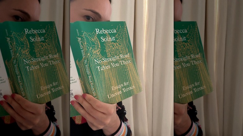 Natalie Portman holding a copy of No Straight Road Takes You There by Rebecca Solnit