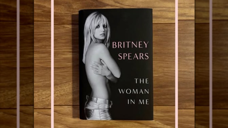 A copy of the book "The Woman In Me" laying on a wooden table