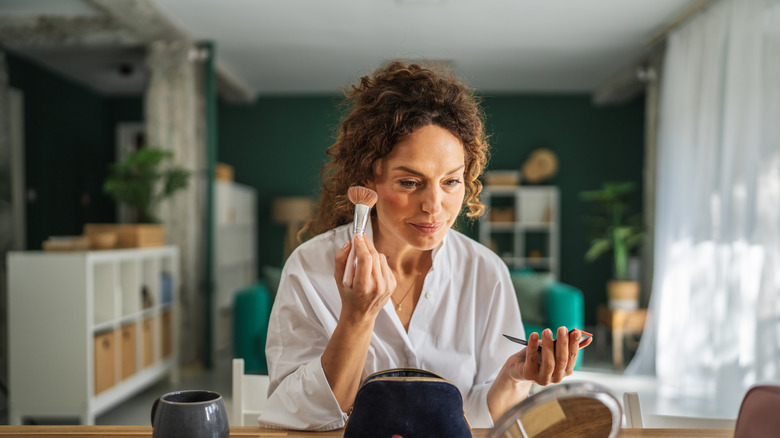 Older woman applying makeup