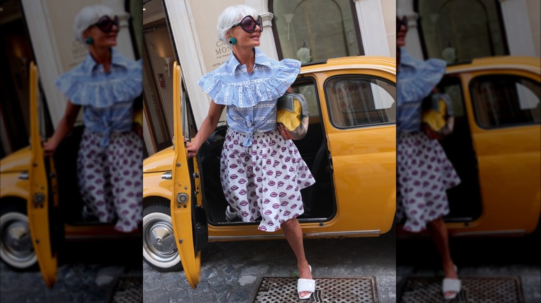 Grece Ghanem in a blue shirt and a patterned skirt stepping out of a cab