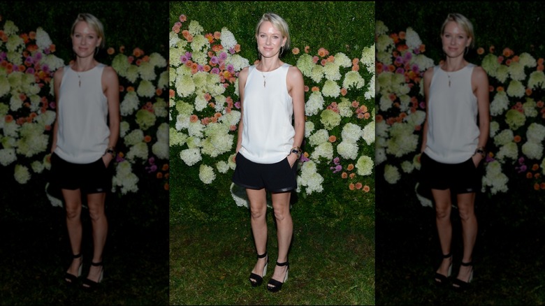 Naomi Watts wearing white blouse and black shorts with leather hem