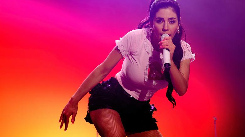 MARINA performing with a microphone in hand