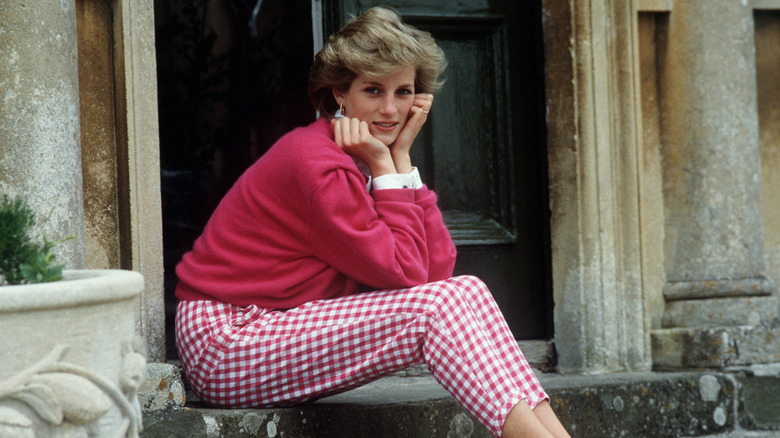 Princess Diana in casual pink attire sitting on a stoop