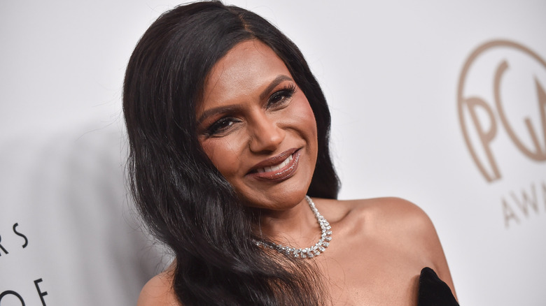 A slanted, close-up photo of Mindy Kaling smiling on the red carpet