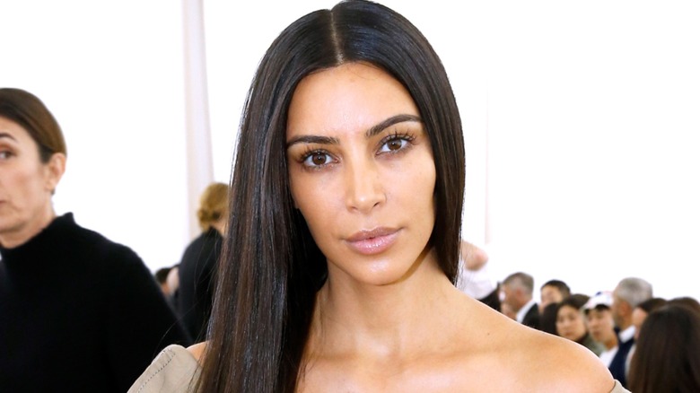 Kim Kardashian posing with straight hair and no makeup at a 2016 Balenciaga fashion show.