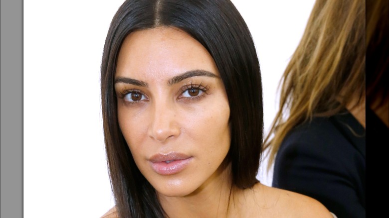 Kim Kardashian not wearing makeup while posing at a 2016 Balenciaga fashion show in Paris.