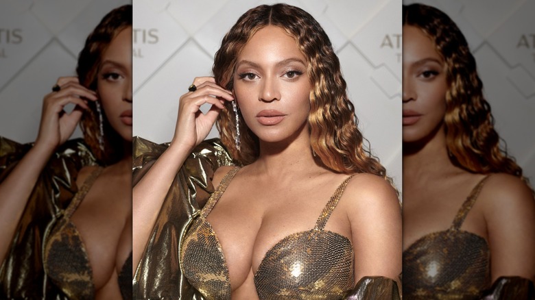 Close-up of Beyoncé pushing her crimped hair out of her face while posing at a red carpet event
