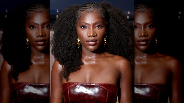 Close-up of Doechii looking into the camera while wearing a strapless garment and statement earrings