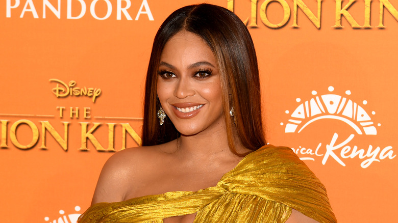Beyoncé smiling while wearing a golden gown at the premiere of 