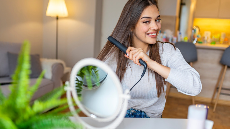 A woman flat ironing her hair