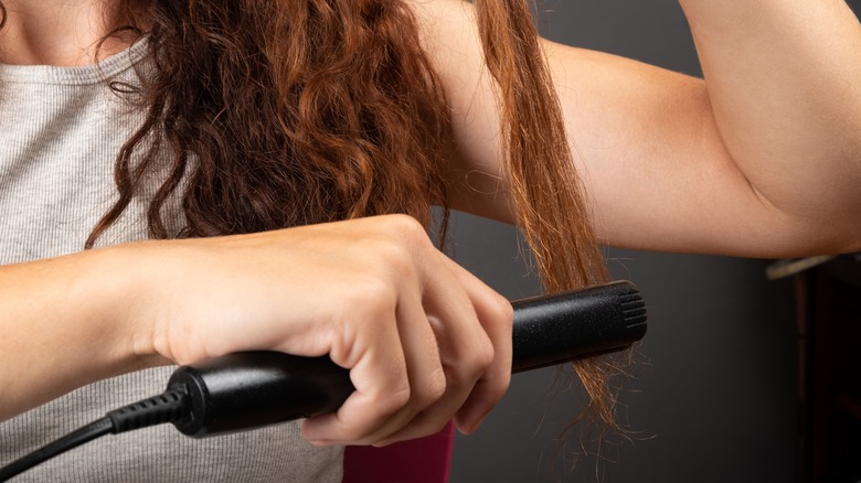 Person flat ironing hair