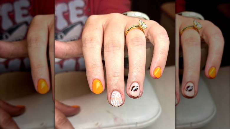 A close-up of an orange, clear and brown football manicure on Instagram