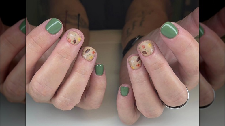 A close up of a green and fall-themed manicure with football details on Instagram