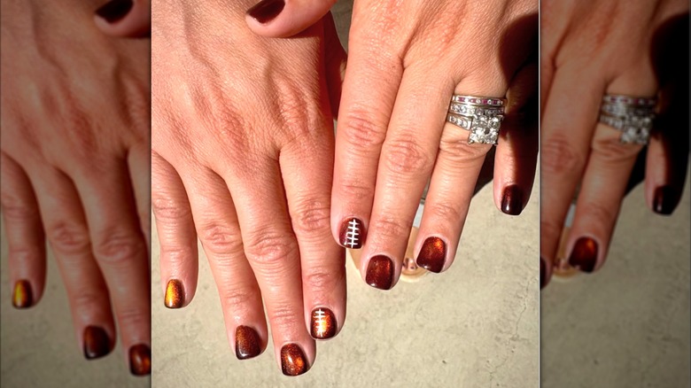 A close up of a brown copper manicure with footballs on some of the nails