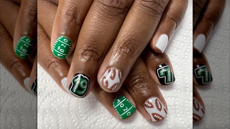 A close up of a green and brown themed football manicure on Instagram
