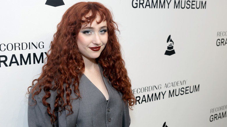 Chappell Roan smiling at a Grammy's event with her cranberry-red curls