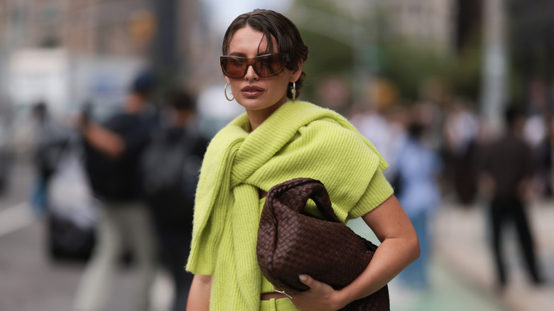 A woman wearing a chartreuse sweater with a brown handbag