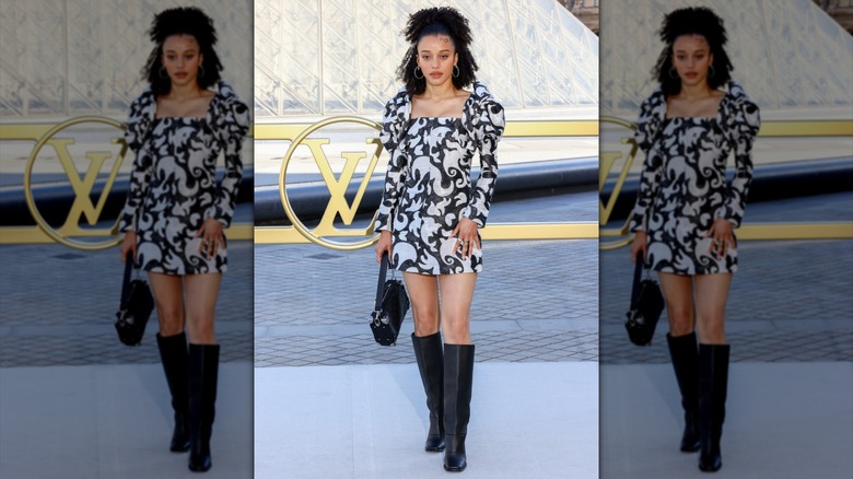 Chase Infiniti attending Paris Fashion Week in a black-and-white mini-dress with a half-up hairstyle