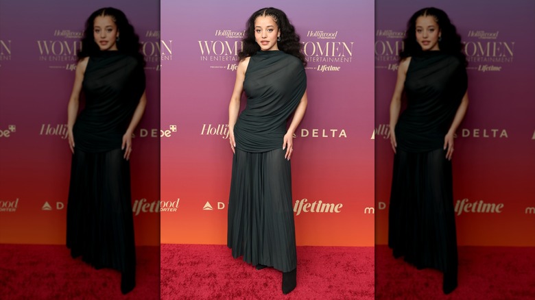Chase Infiniti posing in a black, draped gown at The Hollywood Reporter Women In Entertainment event