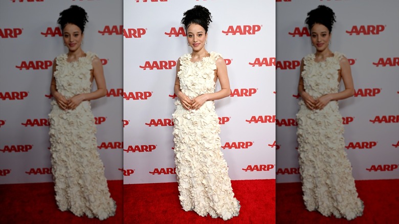 Chase Infiniti smiling at the Annual Movies for Grownups Awards while wearing a floor-length dress decorated with white appliques