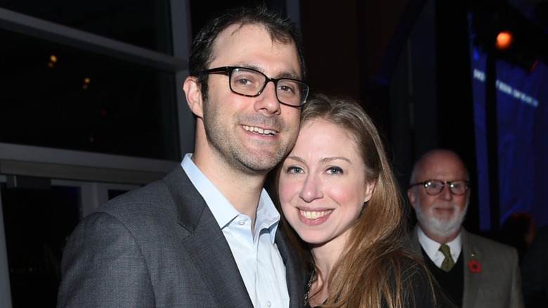 Marc Mezvinsky and Chelsea Clinton smiling and posing together at a party