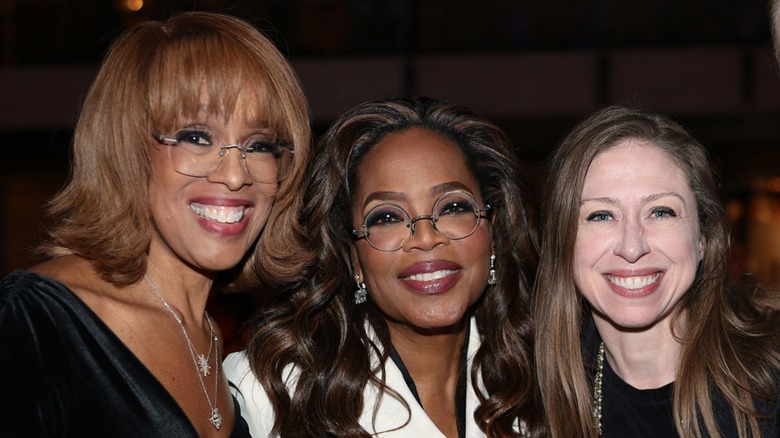Gayle King, Oprah Winfrey, and Chelsea Clinton smiling together at an event