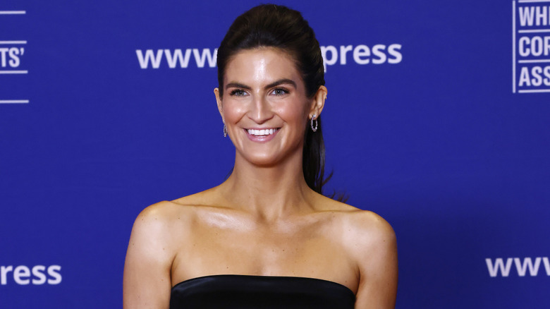 Kaitlan Collins smiling in a strapless gown and ponytail at the 2025 White House Correspondents' Association Dinner