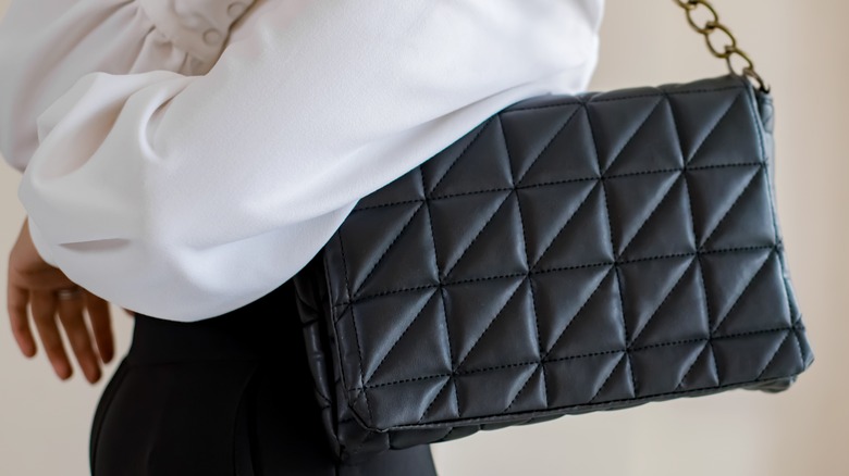 Woman holding black designer shoulder bag 