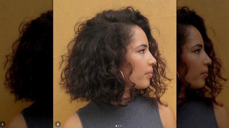 A side profile of a woman with curly hair cut into a shoulder-length bob