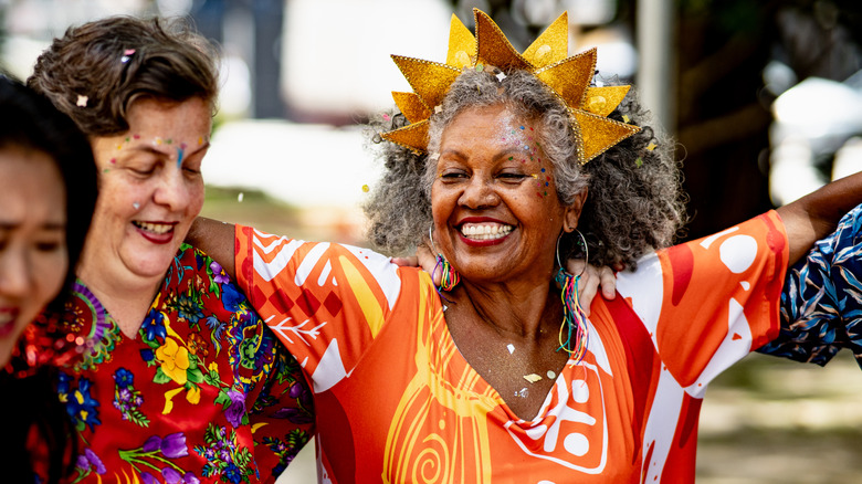 Older black women celebrating wearing a gold crown and face glitter