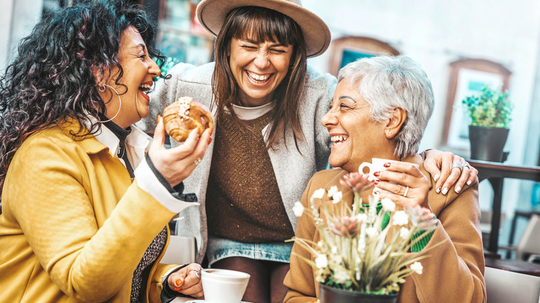 Trio of older women having coffee and pastries smiling