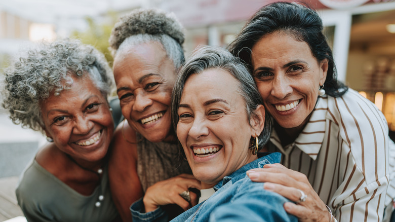 Older group of women smiling and taking a selfie