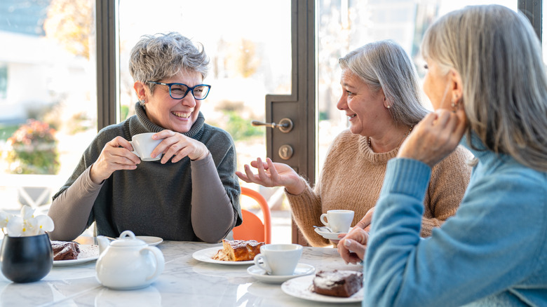 Three older women talking around the table drinking coffee