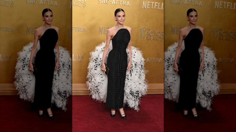 Demi Moore on the red carpet in a black dress with a large white bustle