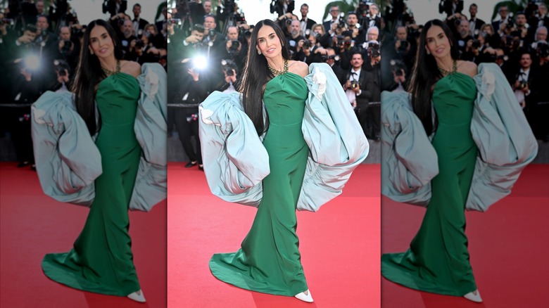 Demi Moore on the red carpet in a green gown with a voluminous blue wrap