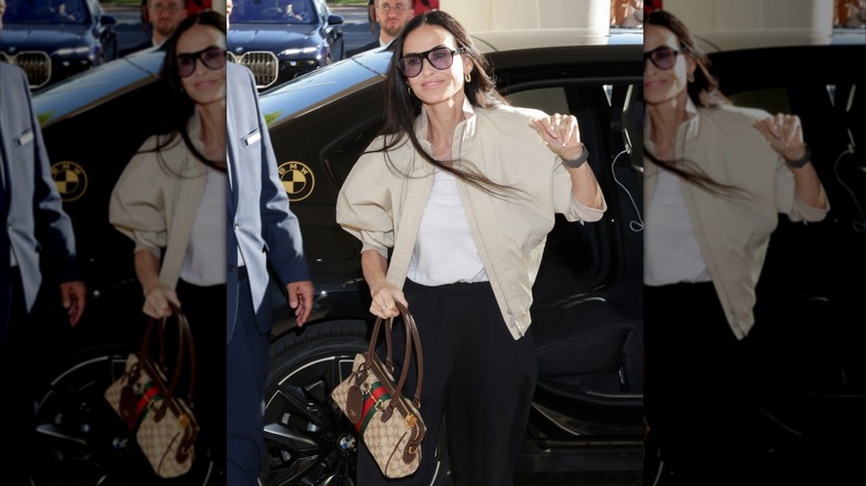 Demi Moore getting out of a car in a casual outfit with black pants, a white shirt, and a tan jacket