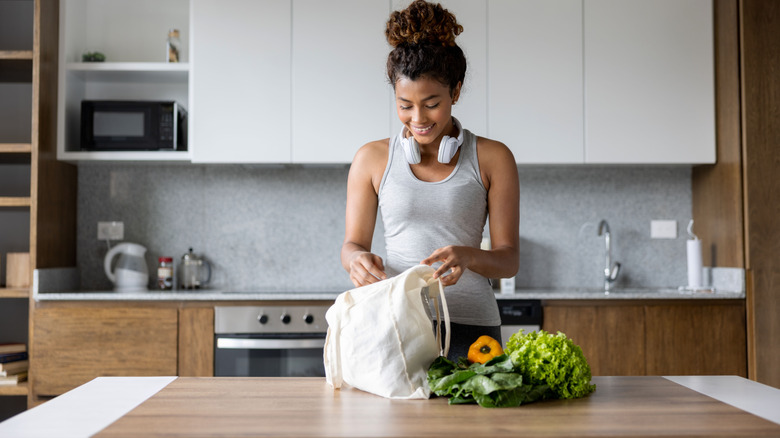 Woman with grocery bag in kitchen