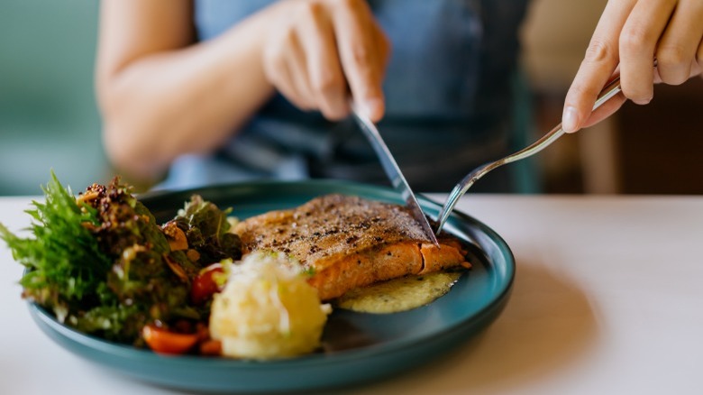 Woman cuts into salmon