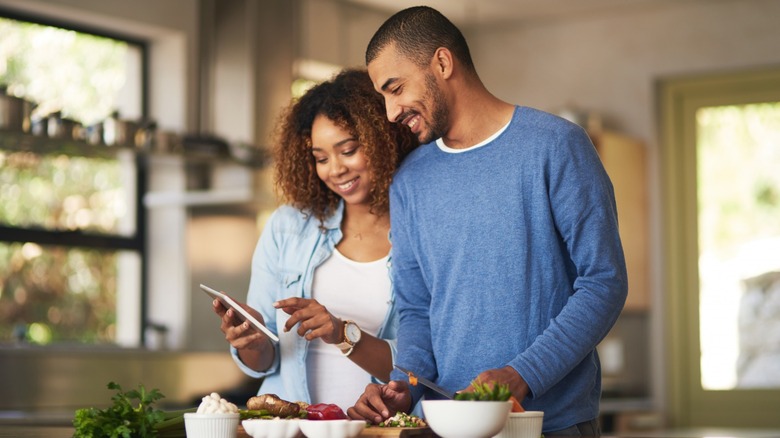 Couple smiles while cooking together 