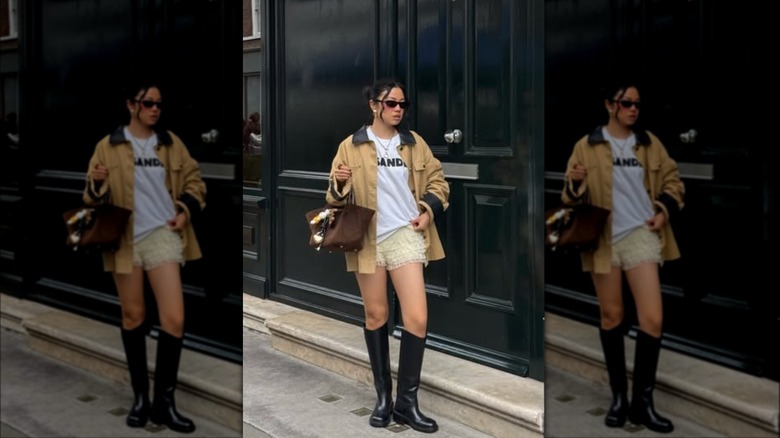 A woman walking on the street in short yellow bloomers and wearing knee-high black boots