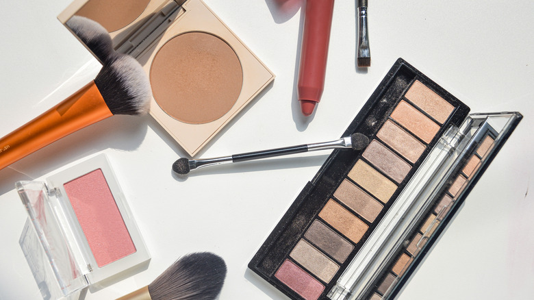 Various makeup products and palettes laying on a white table