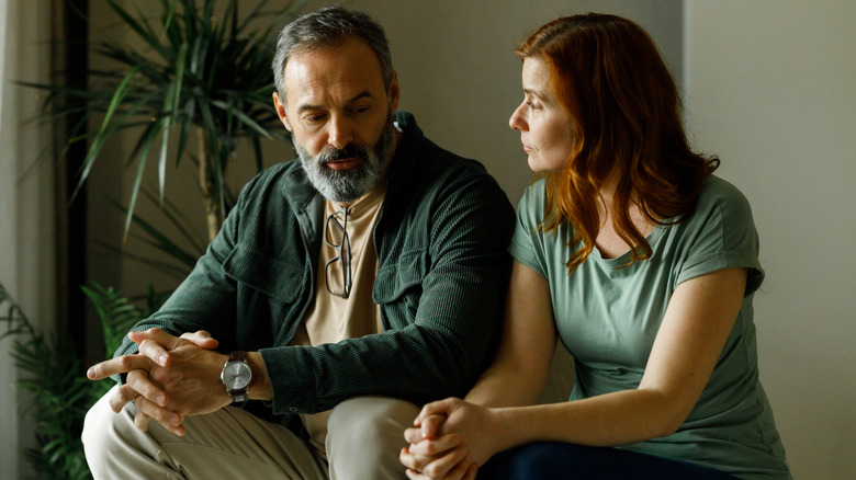 Man and woman sitting next to each other looking sad